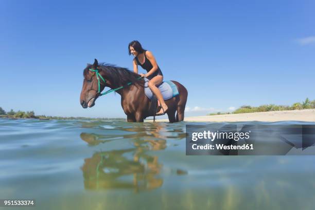 indonesia, bali, woman sitting on horse, in water - bali horse stock pictures, royalty-free photos & images