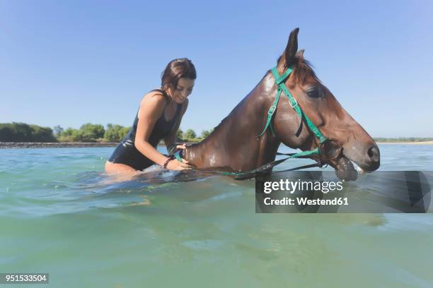 indonesia, bali, woman sitting on horse in water - bali horse stock pictures, royalty-free photos & images