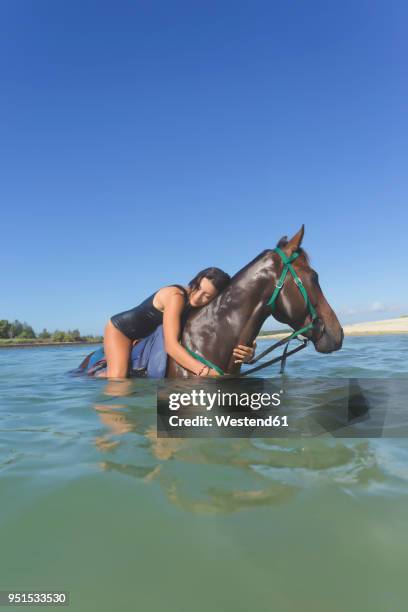 indonesia, bali, woman lying on horse, in water - bali horse stock pictures, royalty-free photos & images