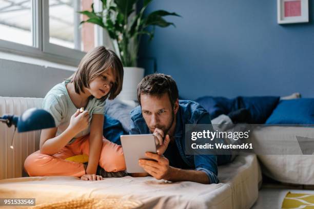 father and son watching a movie on tablet at home - media availability stock-fotos und bilder