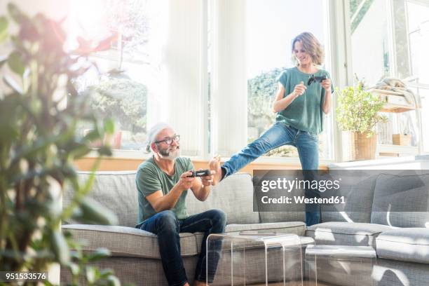 happy mature couple on couch at home playing video game - couple lifestyle jean stock pictures, royalty-free photos & images