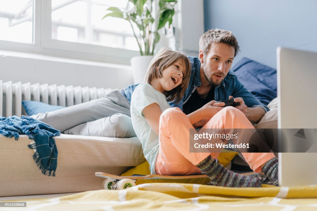 Father and son playing video game together at home