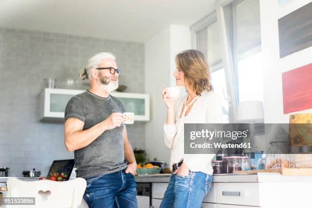 mature couple drinking coffee in kitchen at home - couple 50 55 laptop stock-fotos und bilder