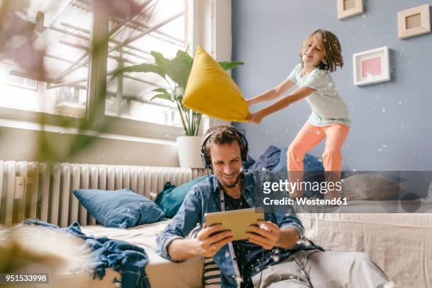 father and son having a pillow fight at home - at home stock-fotos und bilder