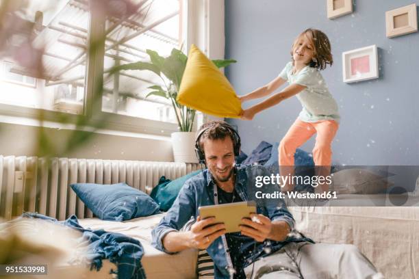 father and son having a pillow fight at home - inmaduro fotografías e imágenes de stock