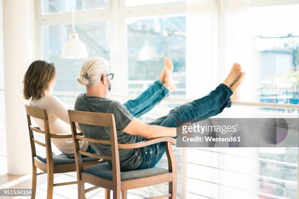 relaxed mature couple sitting on chairs at home with feet up - 50 59 years stock pictures, royalty-free photos & images
