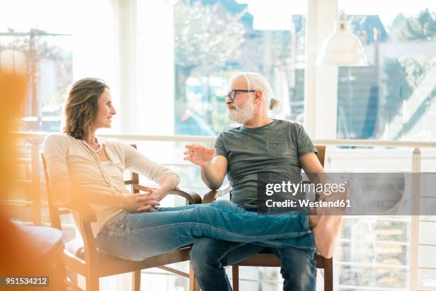 relaxed mature couple talking on chairs at home - 50 59 years home stock pictures, royalty-free photos & images