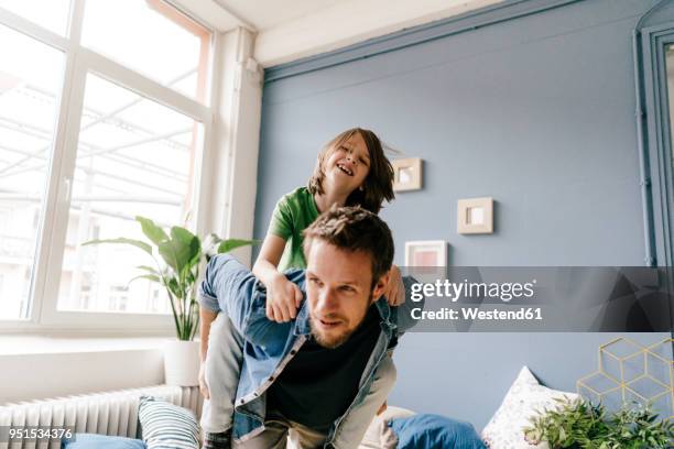 happy father carrying son piggyback at home - carefree kids stock pictures, royalty-free photos & images