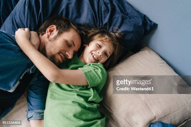 father and son cuddling at home - tranquility stock-fotos und bilder