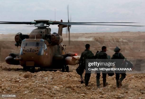 Israeli soldiers walk towards a military helicopter during a search mission for several young people missing near Arava in southern Israel after...