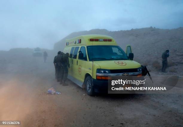 Israeli soldiers and emergency services cover their faces from the dust created from a helicopter during a search mission for several young people...