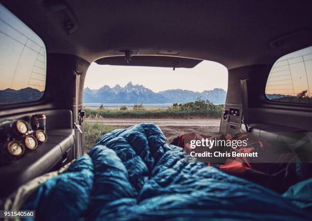 bedrolls inside car with mountain range visible in background, wyoming, usa - achterbak-van-auto stockfoto's en -beelden