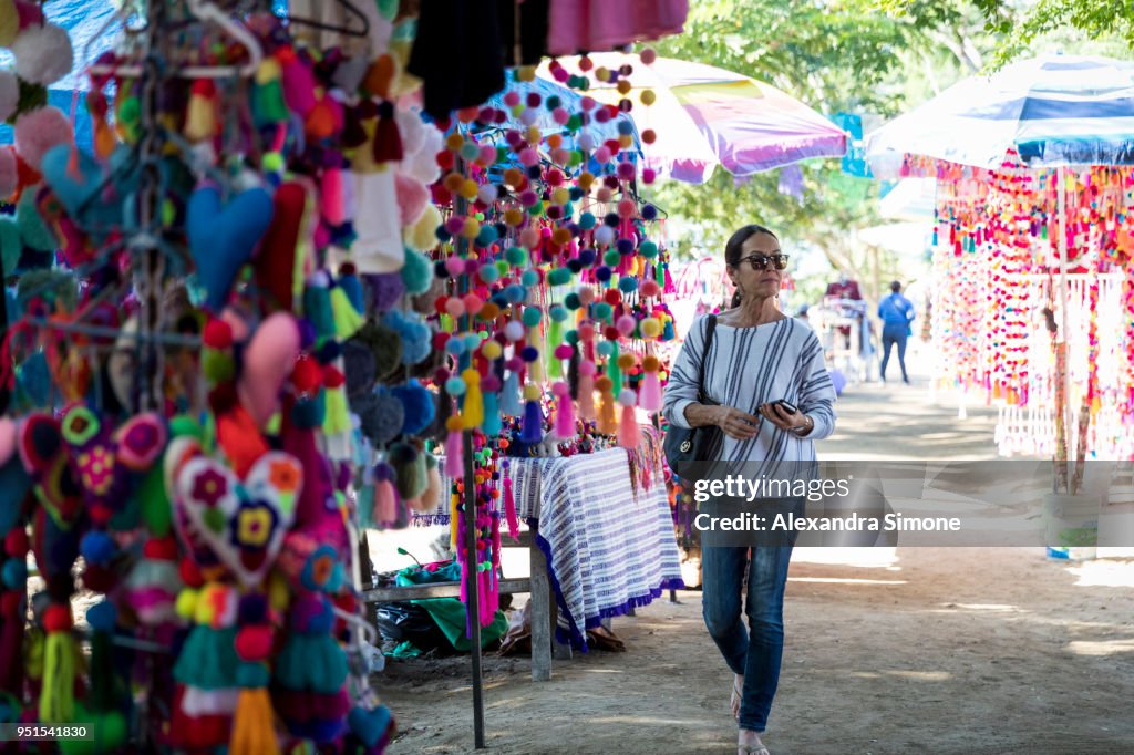 Middle-aged woman walking through art market and looking at colorful merchandise, Sayulita, Mexico