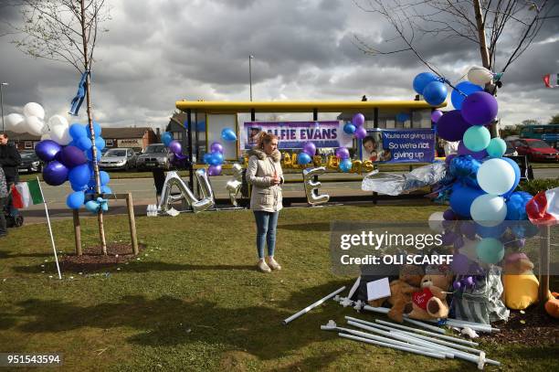 Woman looks at a collection of balloons and children's toys, left by supporters of British toddler Alfie Evans, opposite Alder Hey childrens hospital...