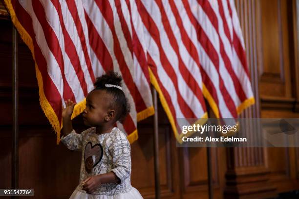 Child touches American Flags behind House Minority Leader Nancy Pelosi as she speaks with journalists' kids during her weekly press conference on...