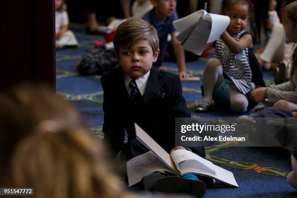 Child listens to House Minority Leader Nancy Pelosi speak with journalists' kids during her weekly press conference on 'Take our Daughters and Sons...