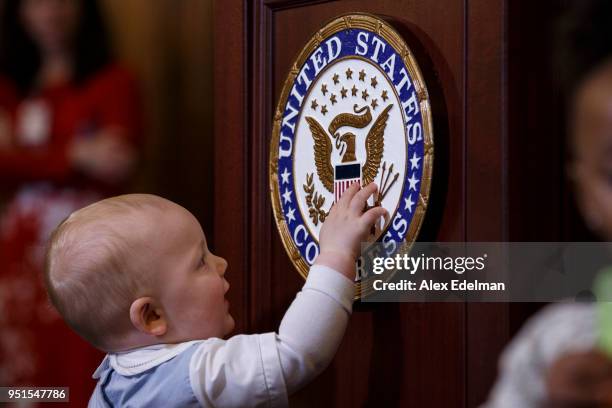 Child touches the House of Representatives Seal as House Minority Leader Nancy Pelosi speaks with journalists' kids during her weekly press...