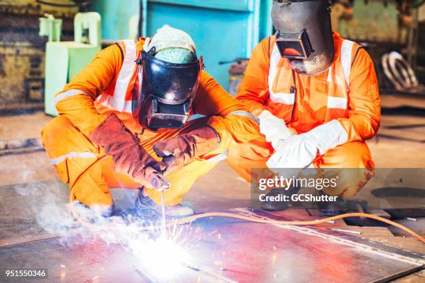 two colleagues welding a large metal sheet. - sheet metal stock pictures, royalty-free photos & images