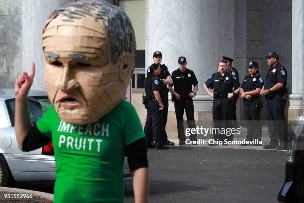Group of U.S. Capitol Police keep eyes on Lukas Ross of Friends of the Earth as he wears a giant mask of Environmental Protection Agency...