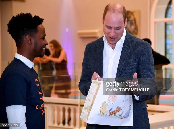 Britain's Prince William, Duke of Cambridge reacts as he receives a gift for his new baby as he attends the opening of Greenhouse Sports Centre in...