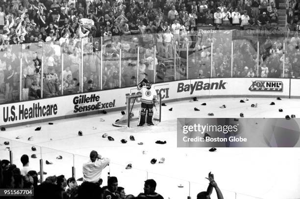 Boston Bruins' goalie Blaine Lacher takes a pause as hats rain down on the ice from the crowd in celebration of teammate Cam Neely's hat trick. The...