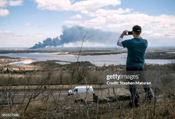 Breven Berg takes a photo of the fire at Husky Oil Refinery in Superior, Wisconsin on April 26, 2018 seen from Duluth, Minnesota. At least 11 people...