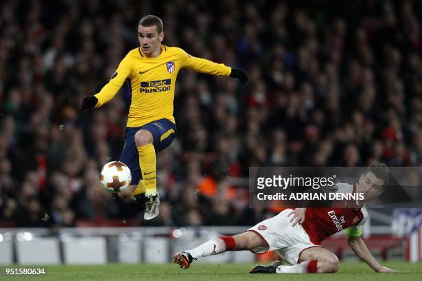 Atletico Madrid's French striker Antoine Griezmann evades a tackle by Arsenal's French defender Laurent Koscielny on his way to scoring their first...