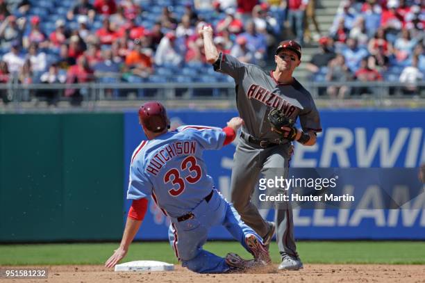 Nick Ahmed of the Arizona Diamondbacks turns a double play as Drew Hutchison of the Philadelphia Phillies slides under the throw in the third inning...