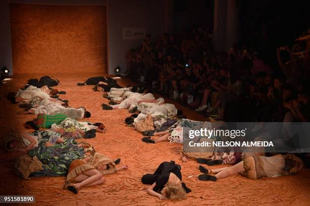 Models lie on the catwalk as they present creations from a collection by Ronaldo Fraga dedicated to the November 5, 2015 environmental disaster at...