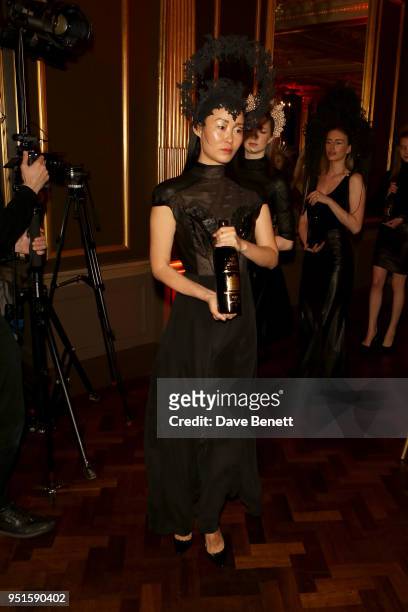 Model holds wine during a fashion show by Pritch London at the Le Cercle SGC Dinner, 'A Golden Affair' at Cafe Royal on April 26, 2018 in London,...