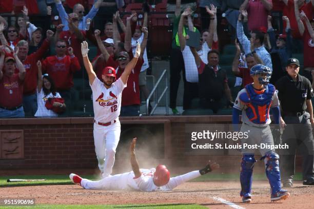 The St. Louis Cardinals' Jose Martinez, middle, scores the game-winning run behind New York Mets catcher Jose Lobaton on a single by Dexter Fowler in...
