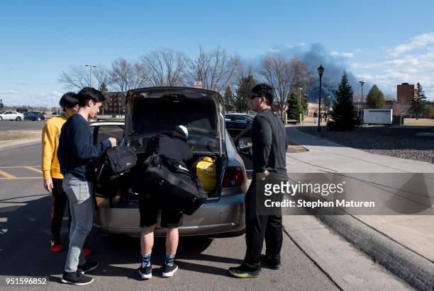 Smoke billows in the background as students at the University of Wisconsin-Superior load up a car on April 26, 2018 in Superior, Wisconsin. The...