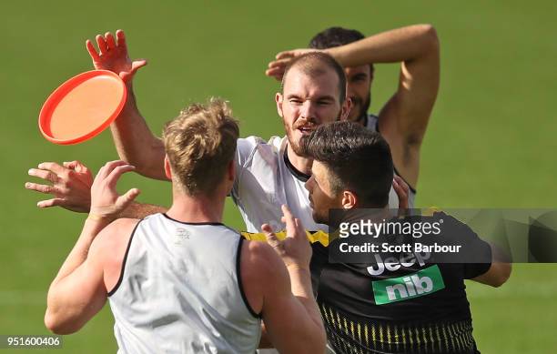 Kamdyn McIntosh of the Tigers is tackled by Josh Caddy of the Tigers and Trent Cotchin of the Tigers as they play a game with a frisbee during the...