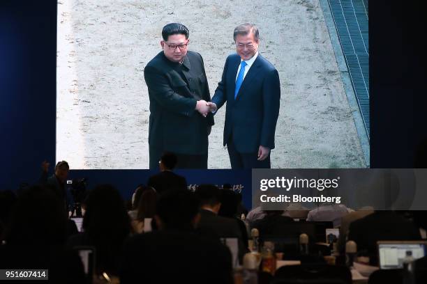 Members of the media watch a screen, showing a broadcast of South Korean President Moon Jae-in and North Korean leader Kim Jong-un shaking hands in...