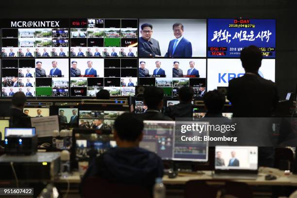 Members of the media watch screens, showing a broadcast of South Korean President Moon Jae-in and North Korean leader Kim Jong-un shaking hands in...