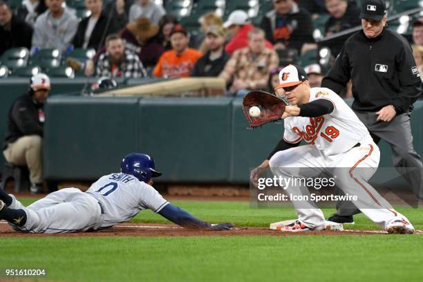 Baltimore Orioles first baseman Chris Davis takes a throw as Tampa Bay Rays center fielder Mallex Smith dives back to first base during the game...