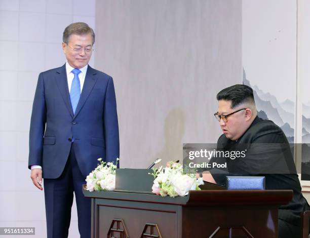 North Korean leader Kim Jong Un signs the guest book as South Korean President Moon Jae-in looks on in the Peace House for the Inter-Korean Summit on...