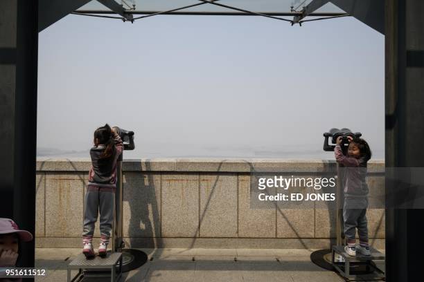 Children look through binoculars towards North Korea at a viewing deck of an observatory overlooking the Demilitarized Zone in Paju on April 27,...