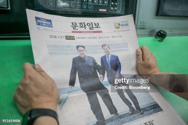 An employee checks a copy of the Munhwa Ilbo Co. Newspaper, featuring a photograph of South Korean President Moon Jae-in, right, and North Korean...