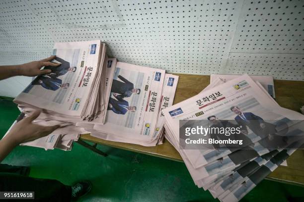 An employee arranges copies of the Munhwa Ilbo Co. Newspaper, featuring a photograph of South Korean President Moon Jae-in, right, and North Korean...