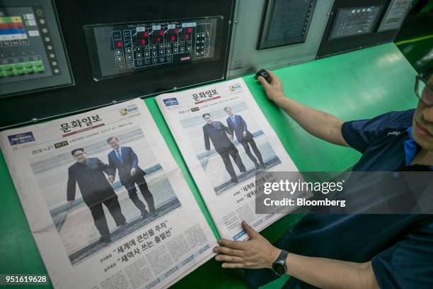 An employee checks a copy of the Munhwa Ilbo Co. Newspaper, featuring a photograph of South Korean President Moon Jae-in, right, and North Korean...