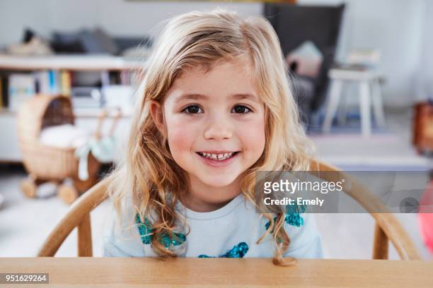 portrait of young girl, sitting at table, smiling - mädchen stock-fotos und bilder