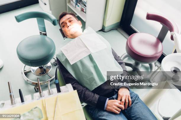 male patient in dentist chair, elevated view - dentists chair stock pictures, royalty-free photos & images