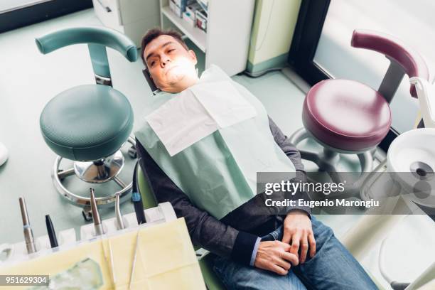 male patient in dentist chair, elevated view - cadeira de dentista imagens e fotografias de stock