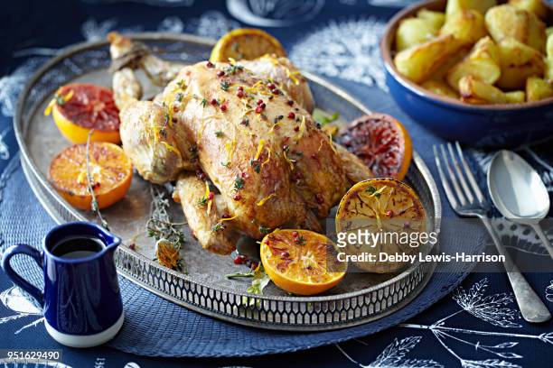 roast chicken with glazed citrus fruits on serving tray - pollo asado fotografías e imágenes de stock