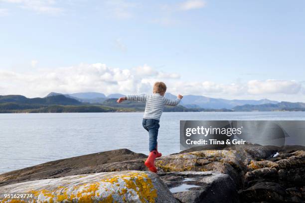 boy jumping rocks by fjord, aure, more og romsdal, norway - condado de more og romsdal fotografías e imágenes de stock