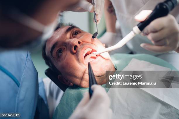 dentist looking into male patients mouth, elevated view - dentist's chair stock pictures, royalty-free photos & images