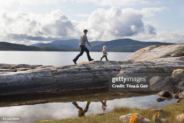 man and son walking on fjord rock formation, aure, more og romsdal, norway - romsdal in norway stockfoto's en -beelden