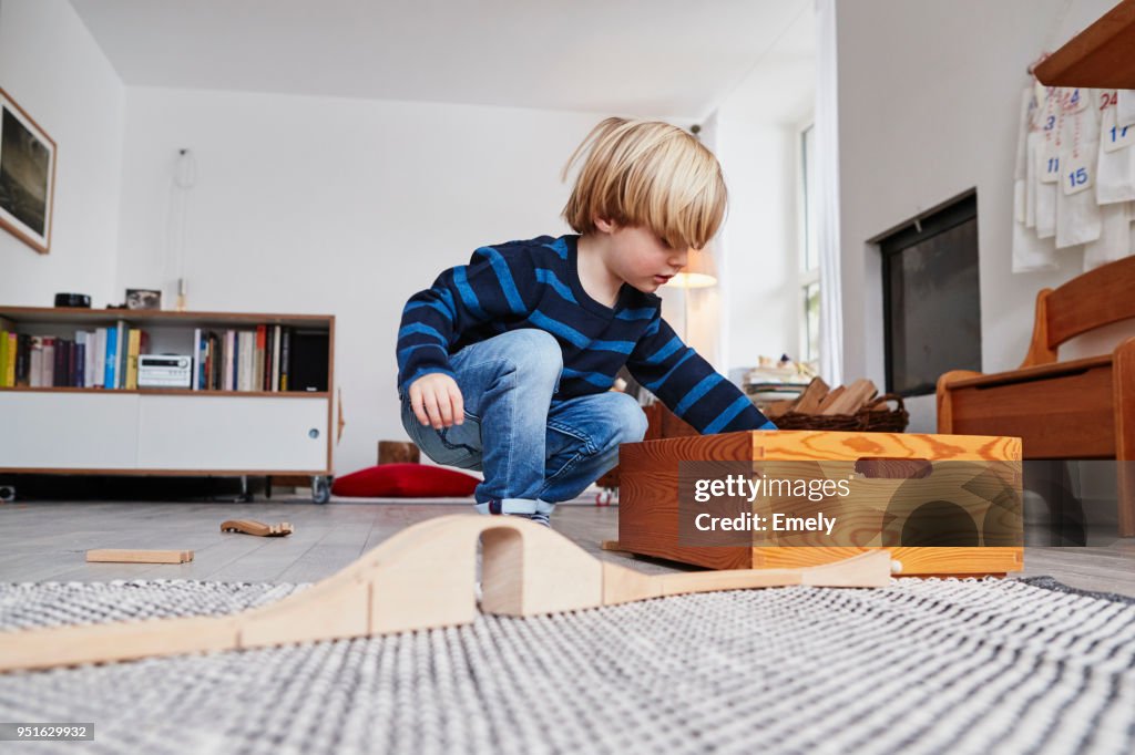 Young boy playing with toys in living room, low angle view