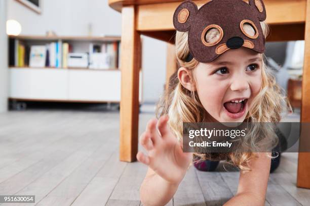 young girl crawling under table, wearing bear mask, laughing - funny bear fotografías e imágenes de stock